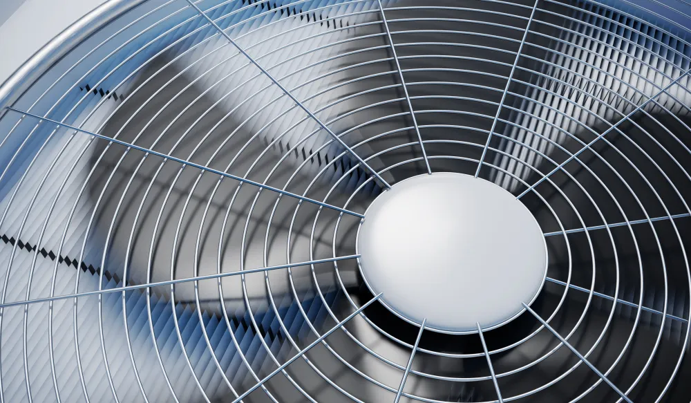 Close-up of an air conditioner condenser fan behind its protective grille